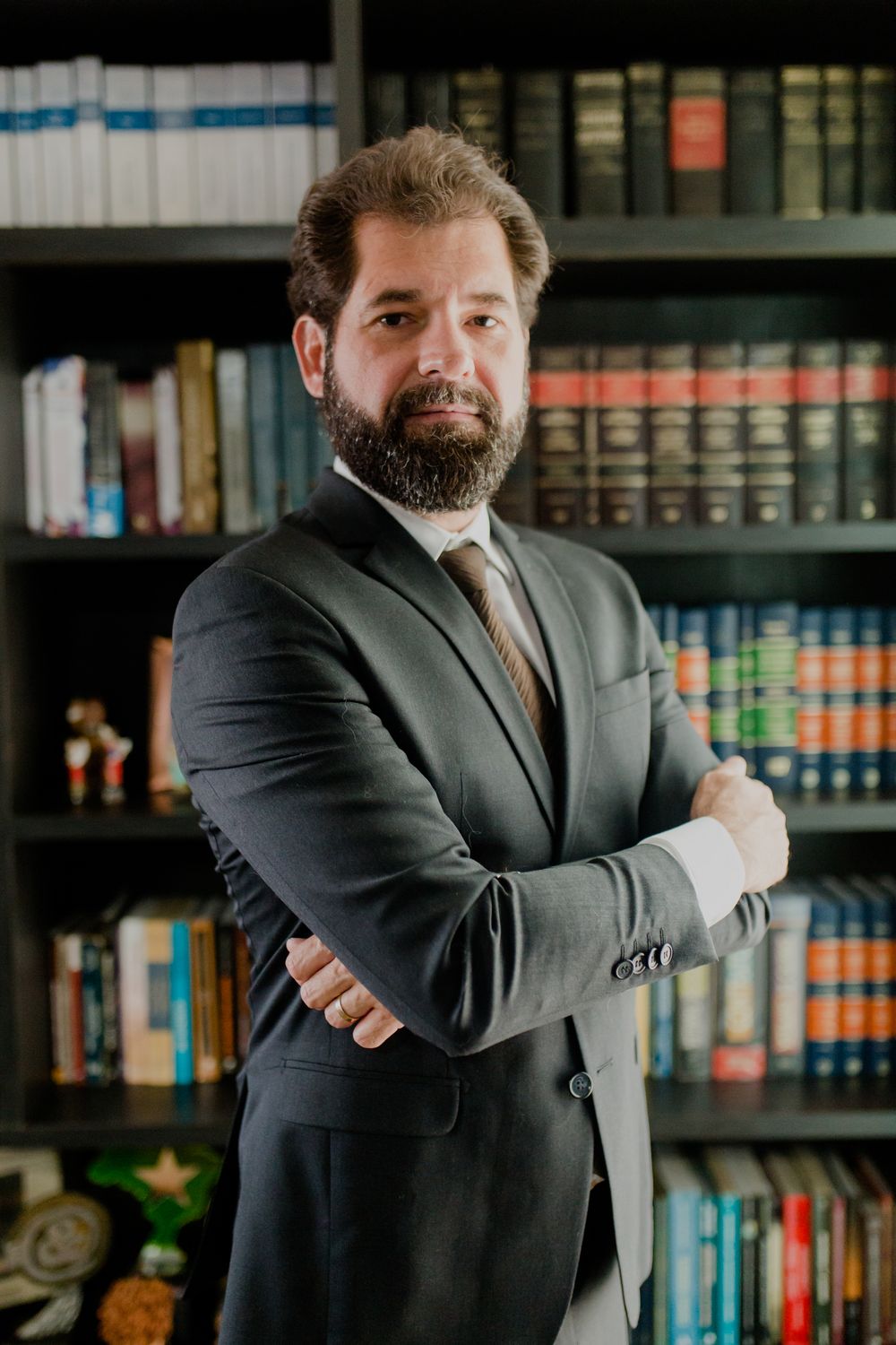 Advogado especialista em Direito Internacional em frente à estante de livros jurídicos do escritório